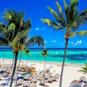 A beach with palm trees, clear turquoise water, and a wooden structure. - Private villa with hot tub & BBQ near PUJ (Punta Cana)