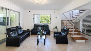 Ein modernes Wohnzimmer mit Ledersofas, einem Glastisch und einer Treppe.