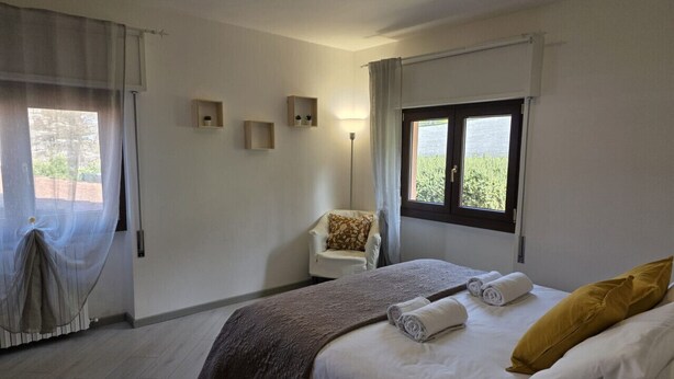 Une chambre à coucher avec un lit, une chaise, une fenêtre et une lampe.
