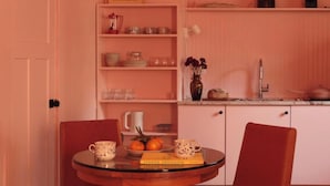 Una cocina con una mesa redonda, dos sillas y varios utensilios de cocina en estanterías.