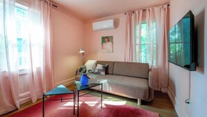 Una sala de estar con un sofá, una mesita, una lámpara y un televisor.