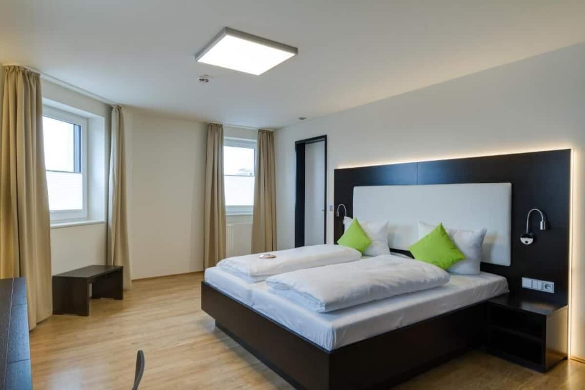 Een moderne hotelkamer met een groot bed, twee nachtkastjes en een plafondlamp.