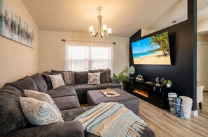 Una sala de estar moderna con un sofá seccional, un televisor de pantalla plana y una chimenea.