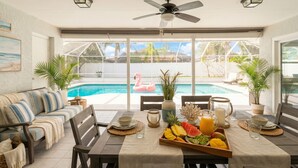 A dining area with a pool view, a sofa, and a fruit tray. - Heated Pool & Jacuzzi Pet Friendly- 7 min to Beach No Extra Fees (Palm Coast)