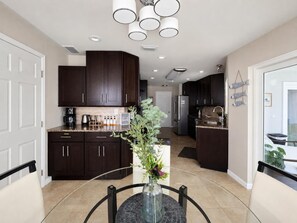 Una cocina moderna con armarios de madera oscura, encimera de mármol y una isla central con un jarrón de flores.