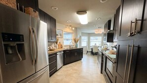 A modern kitchen with stainless steel appliances, dark cabinetry, and a central island. - Heated Pool & Jacuzzi Pet Friendly- 7 min to Beach No Extra Fees (Palm Coast)