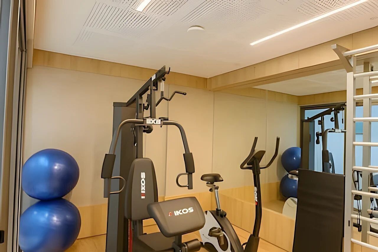 Una palestra con macchinari cardio, palle da ginnastica e uno specchio.