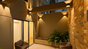 Un intérieur moderne avec une entrée dotée d’une porte en verre, un espace salon et un mur orné d’un motif géométrique.
