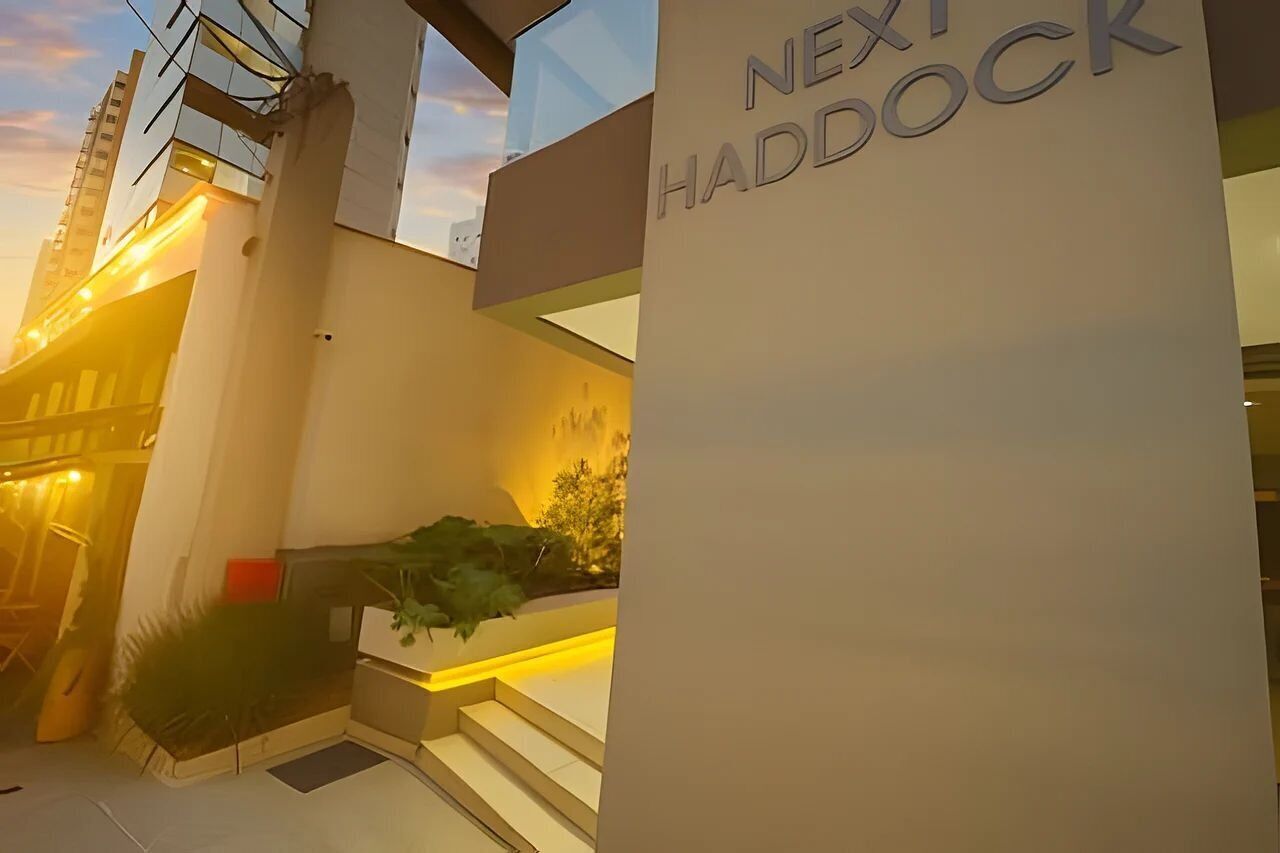 Um edifício moderno com uma placa indicando 'NEXT HADDOCK' e uma escadaria que leva à entrada.
