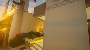 Um edifício moderno com uma placa indicando 'NEXT HADDOCK' e uma escadaria que leva à entrada.