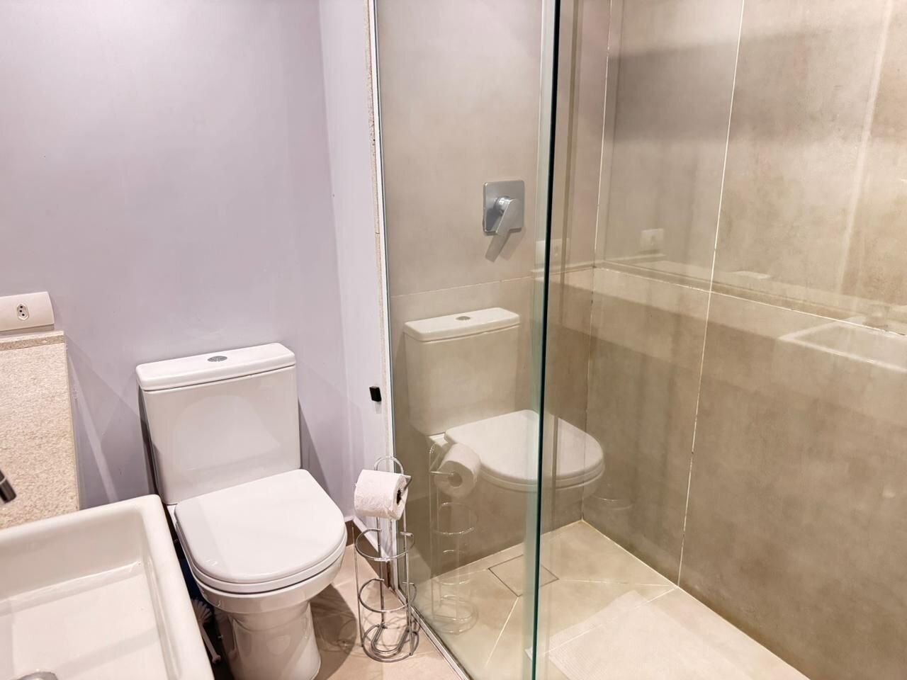 A bathroom with a toilet, a glass shower enclosure, and a sink.