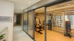 Une salle de sport moderne équipée de matériel d’exercice, d’une barre de traction et d’un support mural.