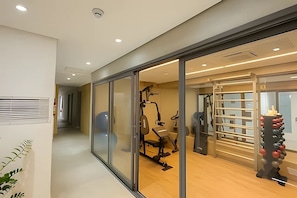 A modern gym with exercise equipment, a pull-up bar, and a wall-mounted rack. - Next Haddock 92 (São Paulo)