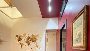 Una sala de estar moderna con un sofá gris, un mural de un mapa mundial y una pared de acento roja.