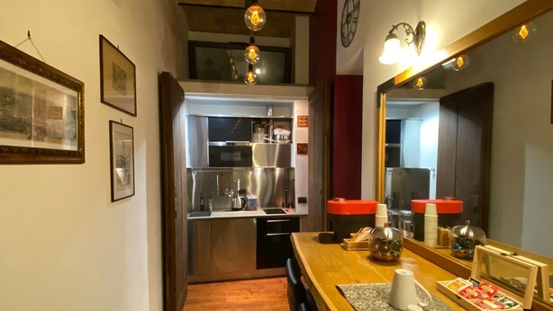Una cocina moderna con electrodomésticos de acero inoxidable, una mesa de comedor de madera con un mantel individual y un espejo sobre la mesa.