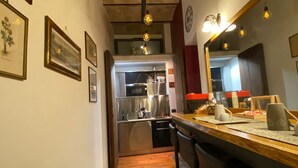 Una cocina estrecha con suelo de madera, electrodomésticos de acero inoxidable e iluminación colgante.