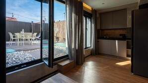 A modern kitchen with large windows, a dining area with outdoor seating, and a view of the backyard. - Dobo Madrid MA24 (Madrid)