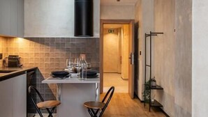 A modern kitchen with a central island, two bar stools, and a dining table set for two. - Dobo Madrid MA24 (Madrid)