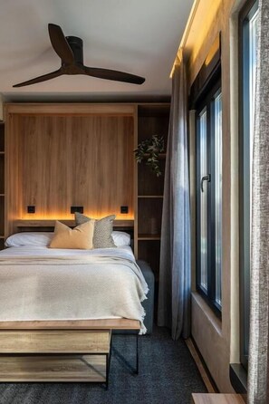 A modern bedroom with a wooden headboard, a ceiling fan, a large window with curtains, and a bedside table. - Dobo Madrid MA24 (Madrid)
