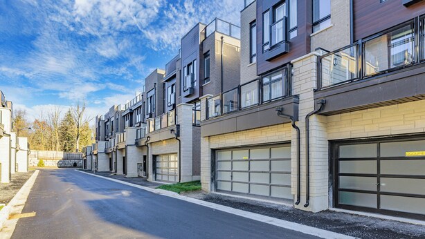 A row of modern multi-story residential buildings with garage doors, a clear sky, and a street in the foreground. - Modern 4Bed Home in Richmond Hill /Rooftop Terrace & EV Charger (Richmond Hill)