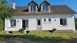 A two-story house with a white exterior, a tiled roof, and a small front porch with potted plants. - Quiet house ideal for a family. (Saint-Aignan)