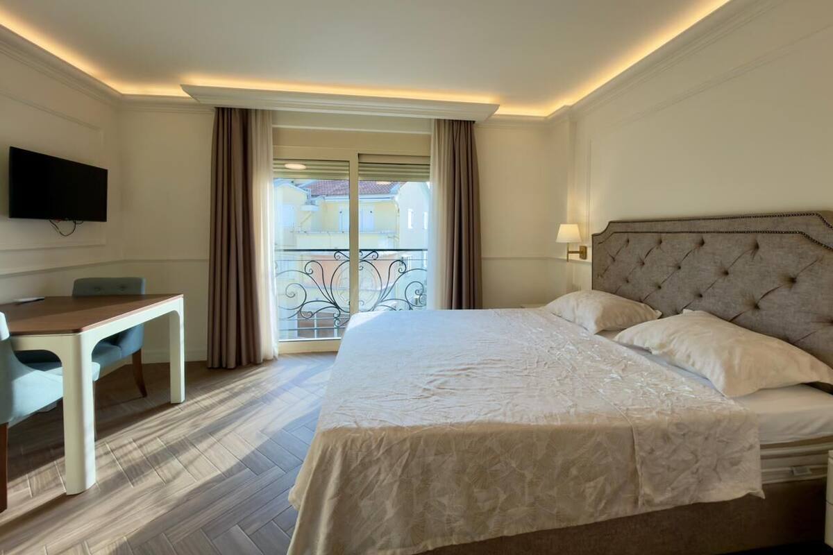 A hotel room with a large bed, a desk, and a TV.
