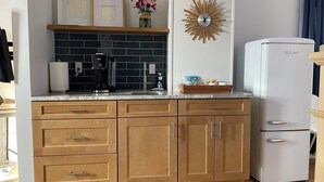A kitchen with wooden cabinets, a white refrigerator, a black coffee maker, and a decorative wall clock.