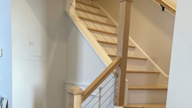 A wooden staircase with a handrail and a landing.