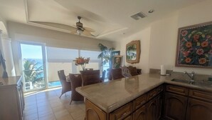 A kitchen with a large island, wooden cabinets, and a view to the outside. - Pedregal Penthouse with Breathtaking Views (Cabo San Lucas)