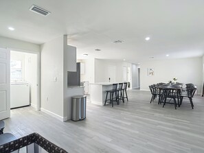 A spacious kitchen with modern appliances, a dining area with multiple chairs, and a trash can. - Spacious Tampa Stay • Large Yard • 15 Guests (Tampa)