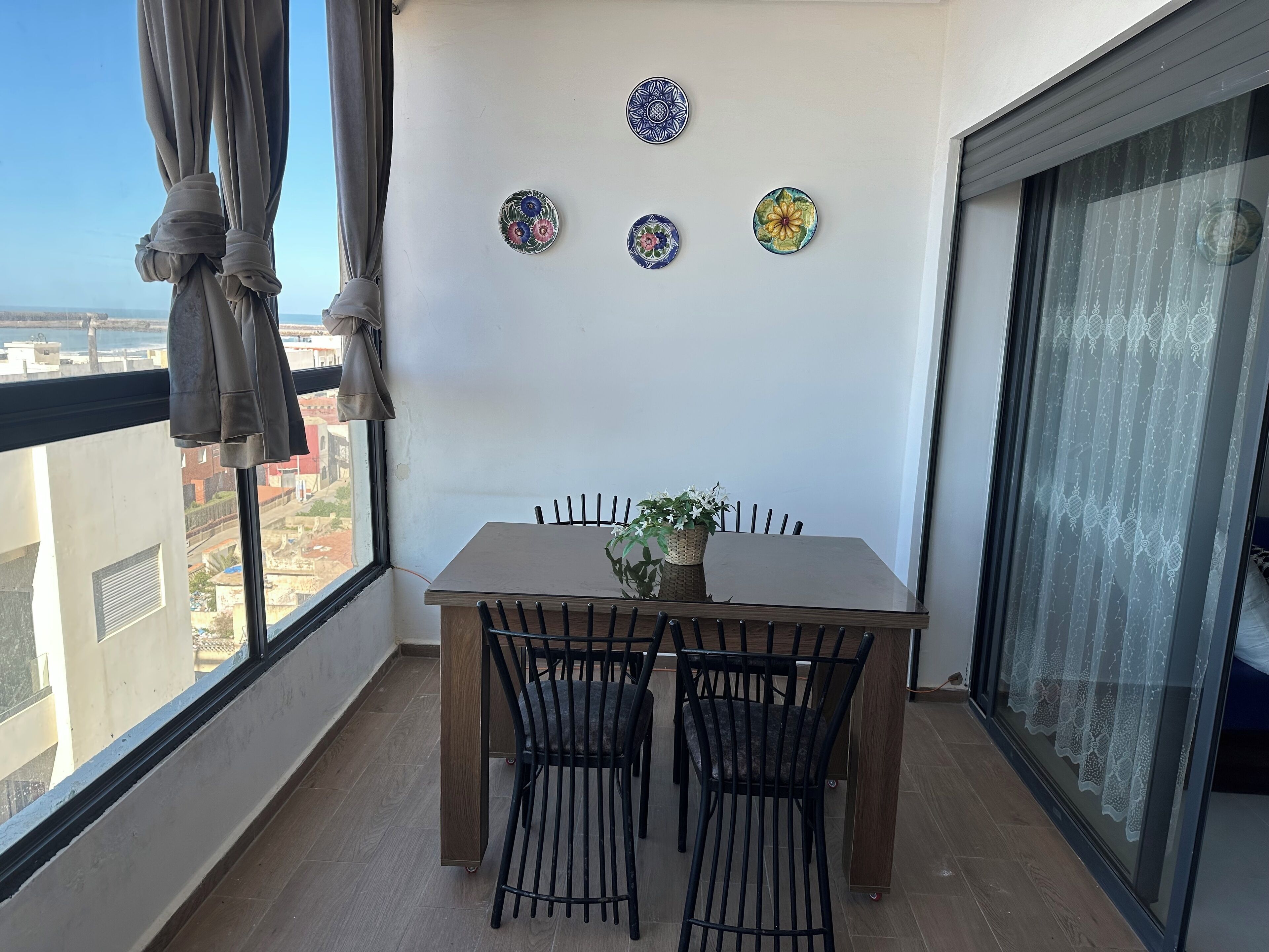 A balcony with a table and chairs, a view of the city, and decorative plates on the wall.