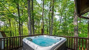 Un bain à remous sur une terrasse en bois, entouré d’arbres.