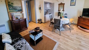 A living room with a sofa, a dining table with chairs, a kitchen area, and a TV. - Comfortable studio in the heart of Arcachon (Arcachon)