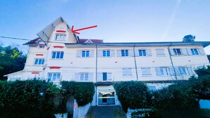 A multi-story building with a slanted roof, a staircase leading to the entrance, and a no parking sign. - Comfortable studio in the heart of Arcachon (Arcachon)