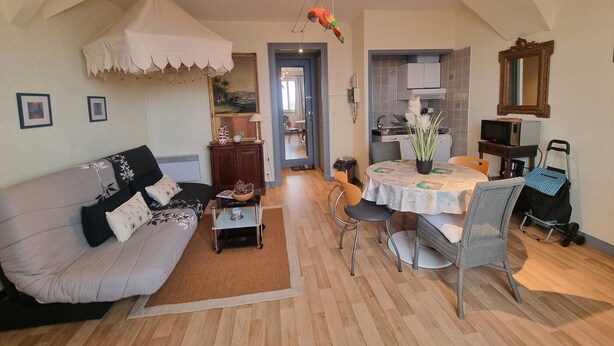 A living room with a sofa, a coffee table, a dining table with chairs, a kitchen area, and a mirror on the wall. - Comfortable studio in the heart of Arcachon (Arcachon)