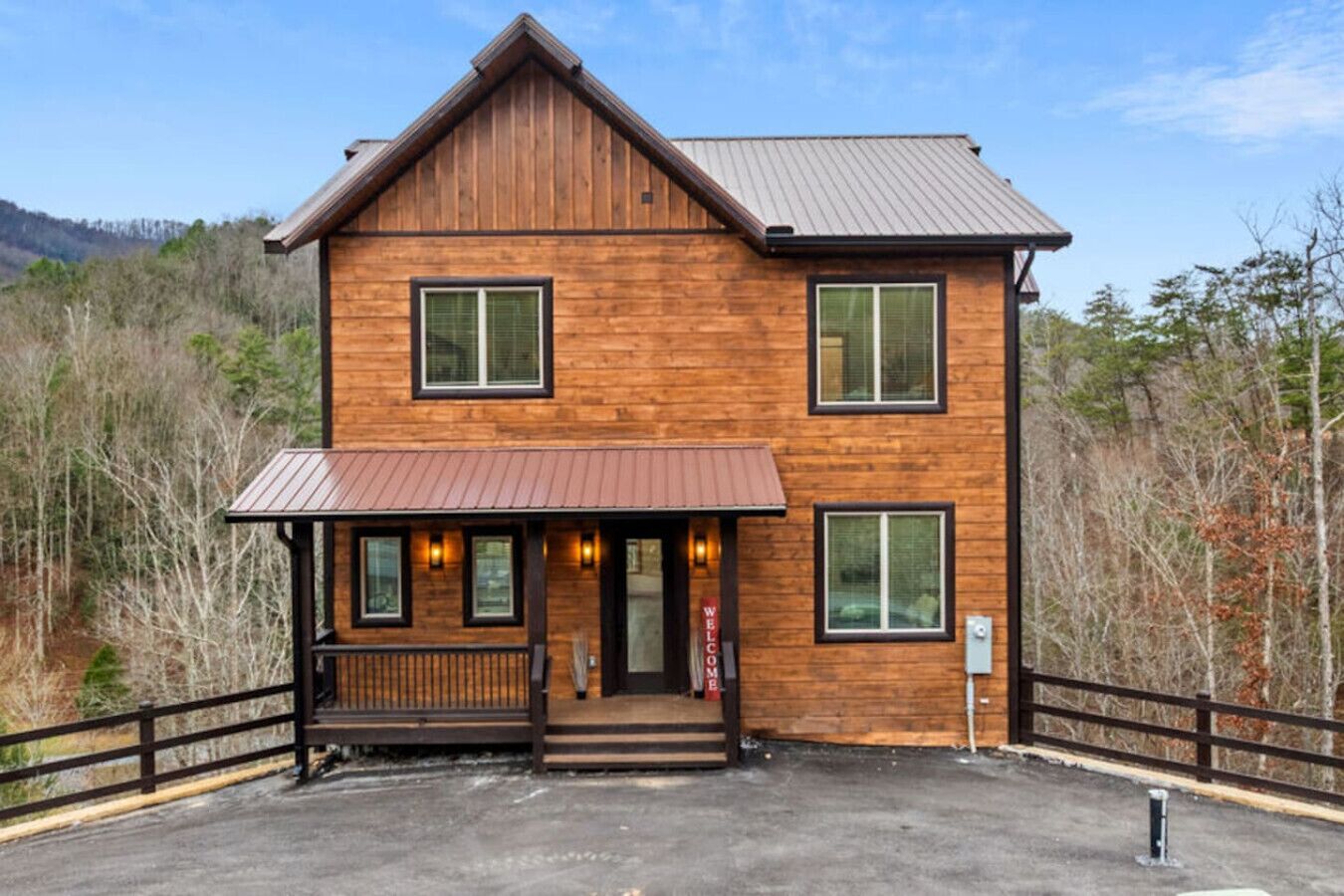 Nestled into the hillside, this modern mountain cabin welcomes you with its charming wood façade, warm glow of porch lanterns, and peaceful forested backdrop. Park with ease and step into your Smoky Mountain getaway.