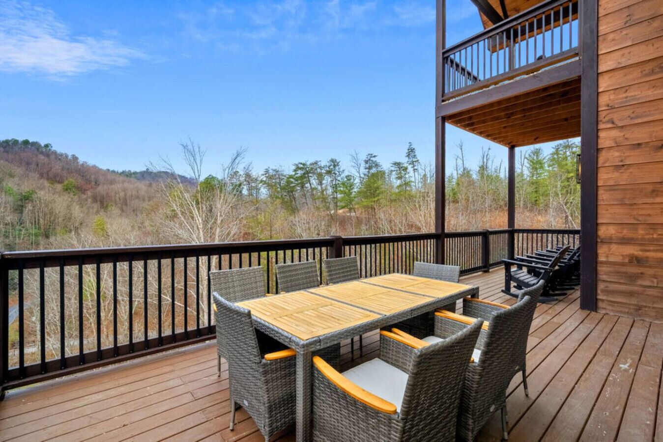 Une terrasse en bois avec une table et des chaises, offrant une vue sur un paysage naturel.