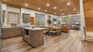 A spacious kitchen with wooden cabinets, a central island, and large windows. - New! 6BR Luxe Pool Cabin*Hot Tub*Games*Fireplace (Sevierville)