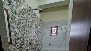 Casa de banho com chuveiro, sanita e lavatório.