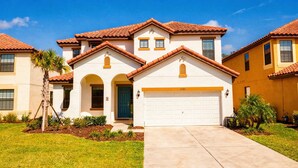 A residential house with a white facade, red-tiled roof, and a garage. - 6BR Family Home w/ Pool Near Disney (Kissimmee)