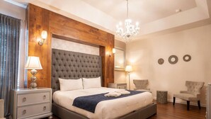 A bedroom with a large bed, wooden paneling, a chandelier, bedside lamps, and a mirror. - 6BR Family Home w/ Pool Near Disney (Kissimmee)