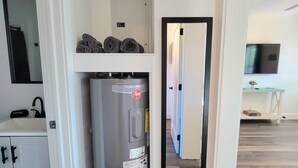 A compact kitchen with a built-in refrigerator, a small shelf with towels, and a mirror.