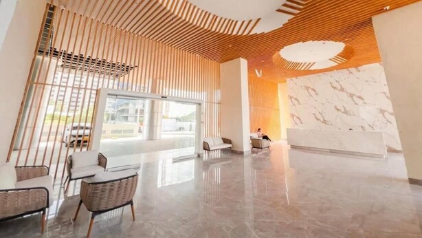 En moderne lobby med himmel i træslats, en receptionsdisk og siddeområder.