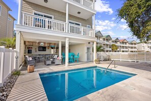 A two-story building with a pool, outdoor seating, and a fenced patio area. - Sunrise on the Marsh (North Myrtle Beach)