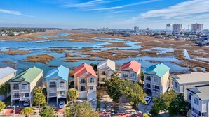 Una zona residencial costera con edificios de varios pisos, un puerto deportivo y un paisaje de marismas.