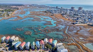 Vista aérea de un pueblo costero con edificios residenciales, un puerto deportivo y una playa.
