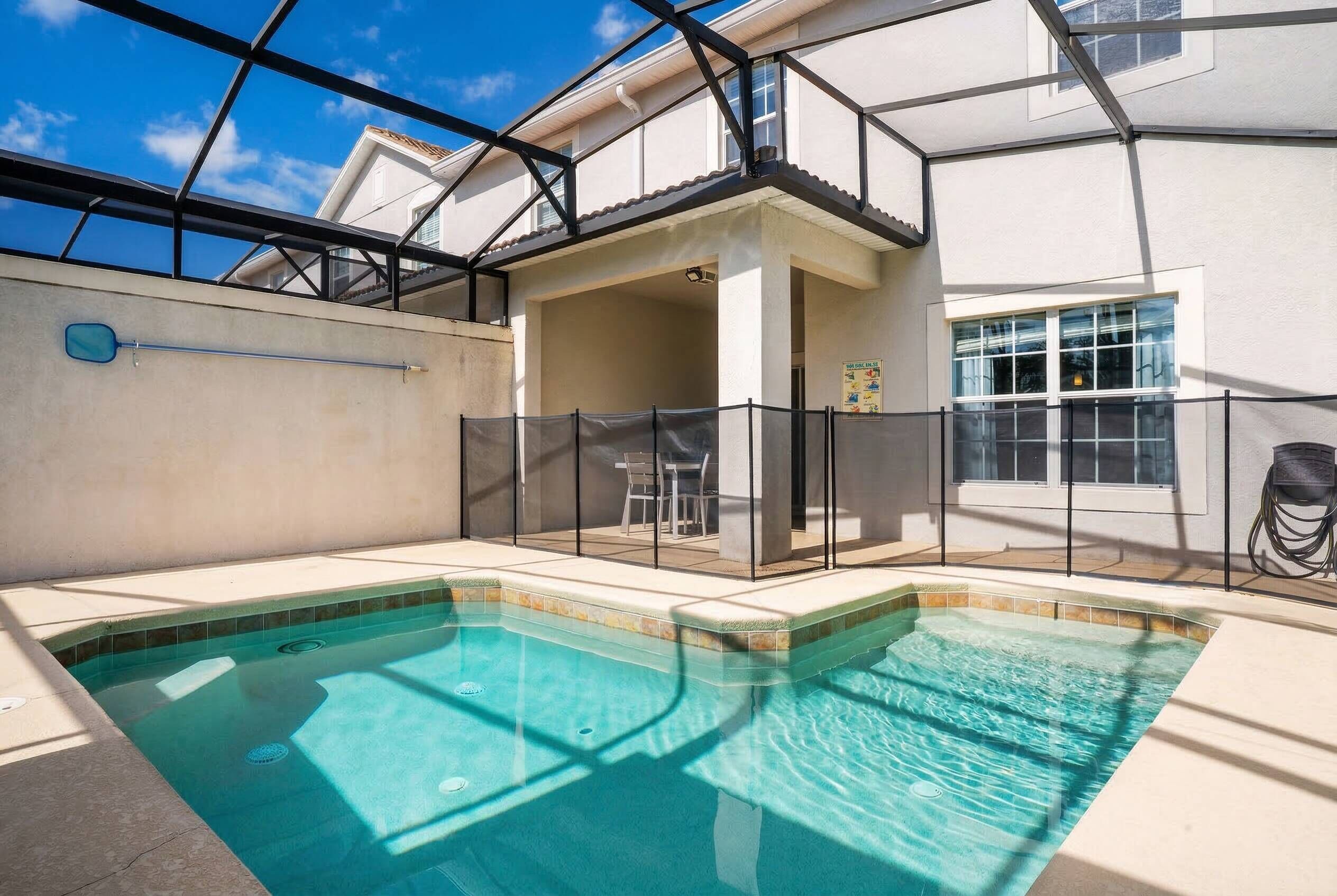 Une piscine avec un patio couvert, une vue sur le ciel et un bâtiment doté d’un balcon.