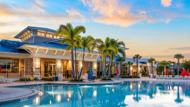 Un hotel con piscina, palme e un cielo al tramonto.