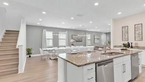 A modern kitchen with a central island, white cabinetry, and stainless steel appliances. - 9BR Pool & Spa Home Near Disney | Encore (Kissimmee)