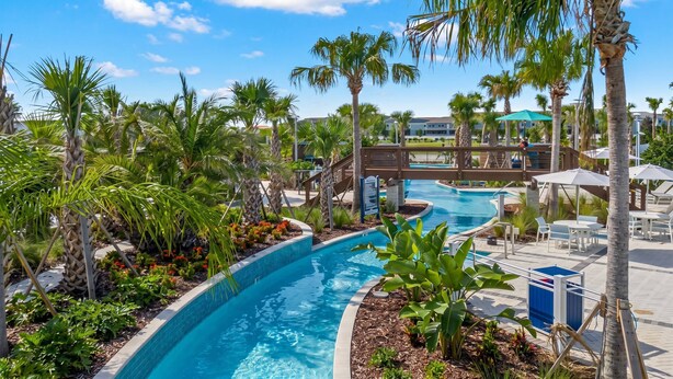 A pool area with palm trees, a wooden bridge, and lounge chairs. - 6BR Family Pool Home at Windsor Cay (Clermont)